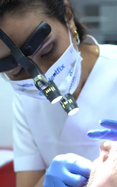 Dr. Ayşe Atay working with dental loupes during a precision veneer preparation